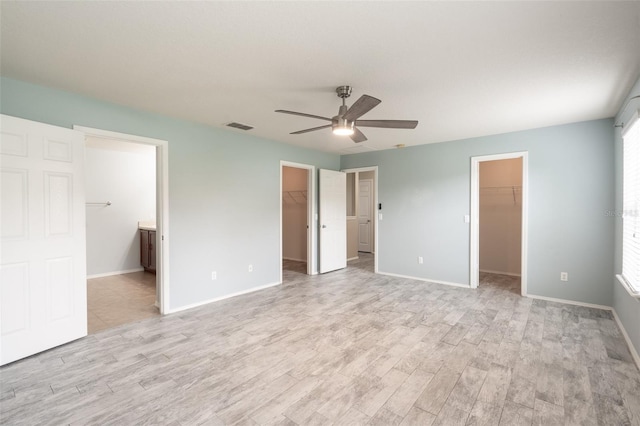 356 Giovani Blvd, Clermont, FL 34715 - unfurnished bedroom with a walk in closet, light wood-style floors, ensuite bathroom, and a ceiling fan
