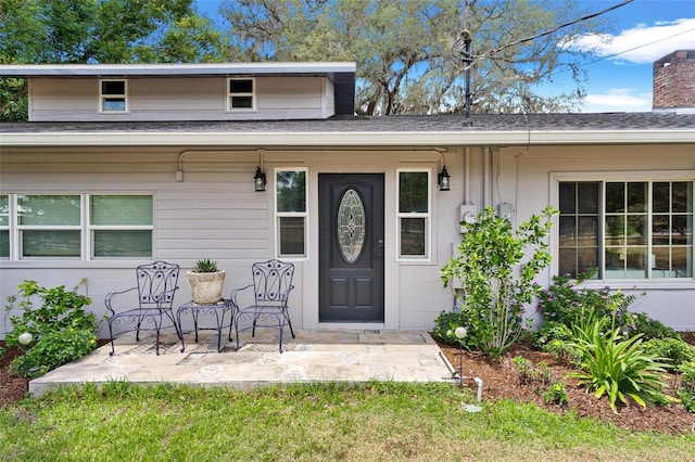 43411 State Road 19, Altoona, FL 32702 - view of exterior entry featuring a patio, roof with shingles, and a chimney