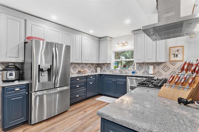 43411 State Road 19, Altoona, FL 32702 - kitchen featuring stainless steel appliances, island range hood, blue cabinetry, light wood-type flooring, and decorative backsplash