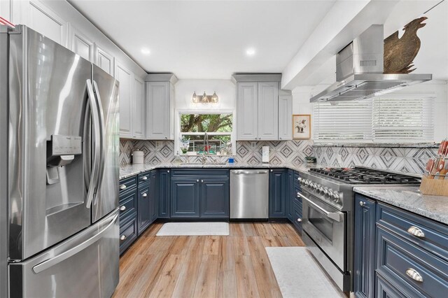 43411 State Road 19, Altoona, FL 32702 - kitchen with stainless steel appliances, blue cabinetry, wall chimney range hood, light wood-style flooring, and recessed lighting