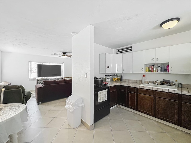 kitchen featuring open floor plan, ceiling fan, a sink, and electric range