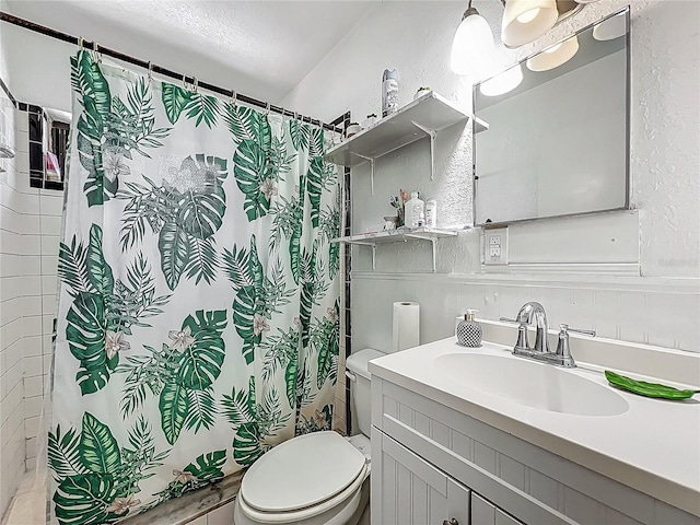 full bath with toilet, curtained shower, vanity, and a textured wall
