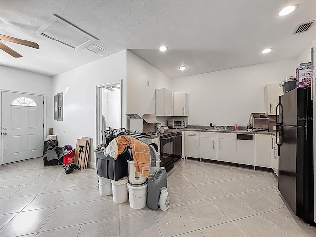 kitchen featuring light tile patterned floors, a sink, freestanding refrigerator, white cabinets, and visible vents