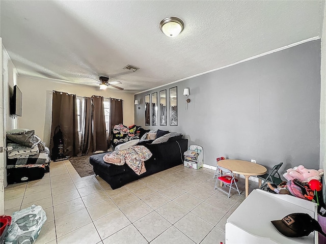 living room with light tile patterned floors, visible vents, ceiling fan, and a textured ceiling