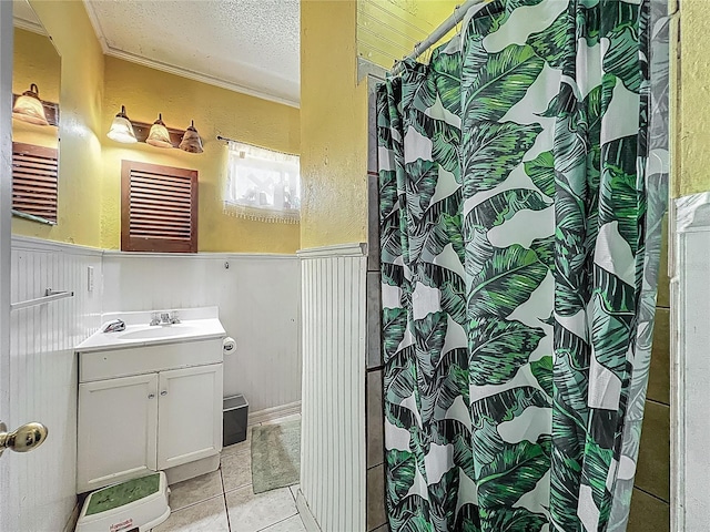 bathroom with a wainscoted wall, crown molding, a textured ceiling, tile patterned flooring, and vanity