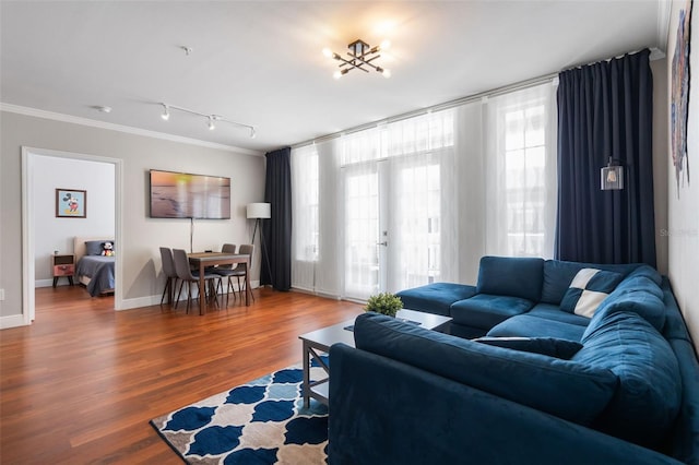 living area with baseboards, ornamental molding, and wood finished floors