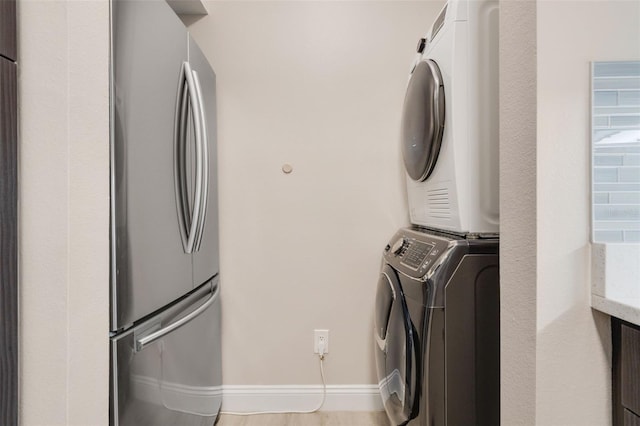 laundry area with baseboards, laundry area, and stacked washer and clothes dryer