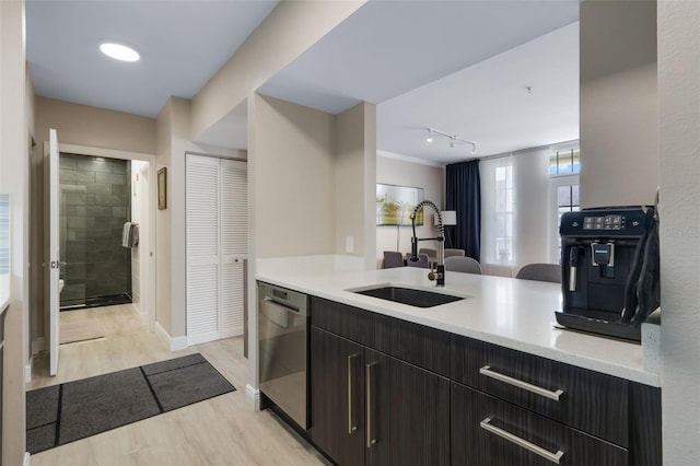 kitchen with stainless steel dishwasher, baseboards, a sink, light countertops, and light wood-type flooring