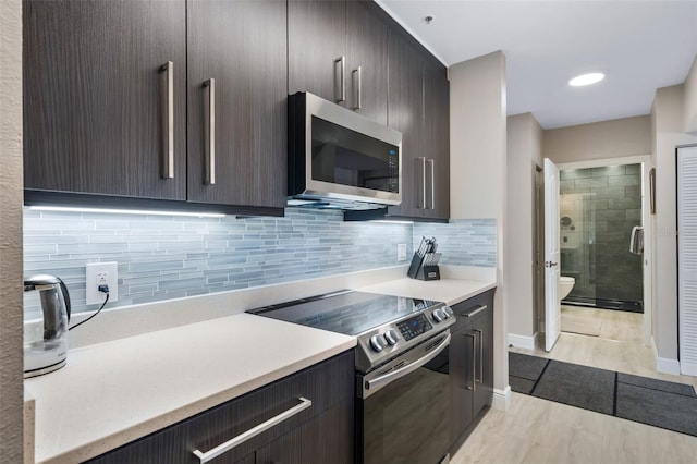 kitchen featuring light countertops, appliances with stainless steel finishes, dark brown cabinets, and tasteful backsplash