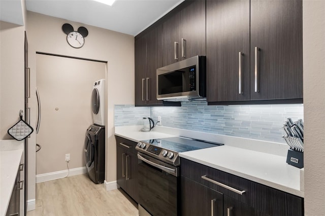 kitchen with stacked washer / dryer, backsplash, light wood-type flooring, and appliances with stainless steel finishes