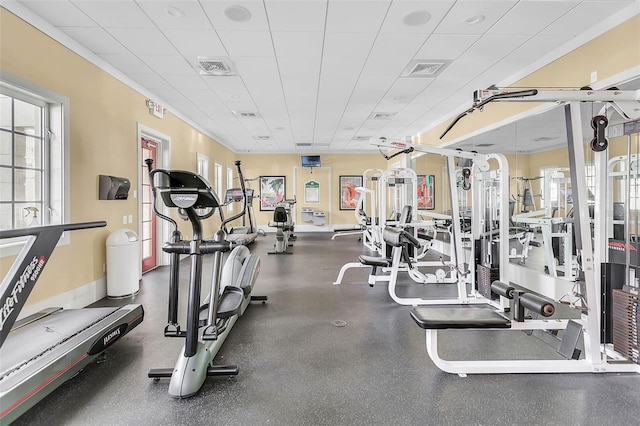 workout area featuring a drop ceiling, baseboards, a healthy amount of sunlight, and visible vents