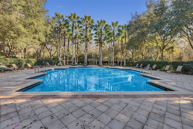 pool with a patio area and fence