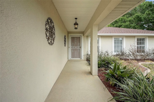 view of exterior entry featuring stucco siding and a shingled roof