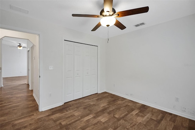unfurnished bedroom with wood finished floors, baseboards, a closet, and a ceiling fan