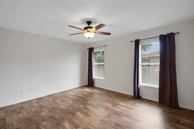 spare room featuring healthy amount of natural light, wood finished floors, a ceiling fan, and baseboards