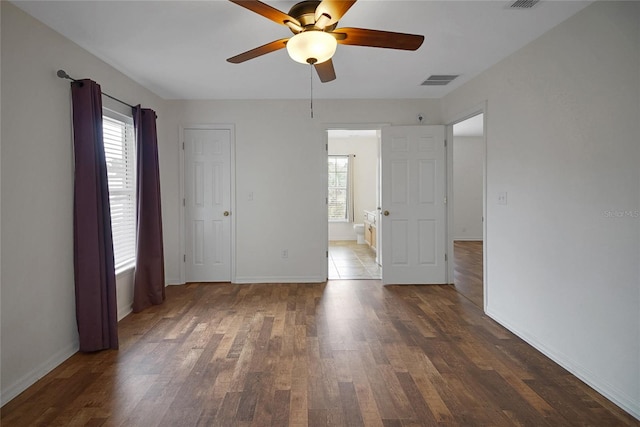 unfurnished bedroom featuring multiple windows, wood finished floors, and baseboards