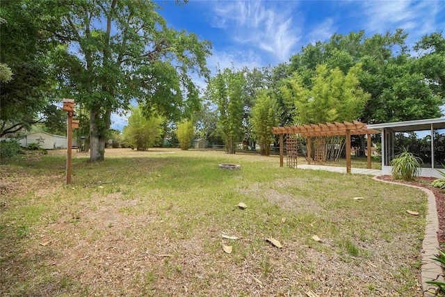 view of grassy yard with a pergola and an outdoor fire pit
