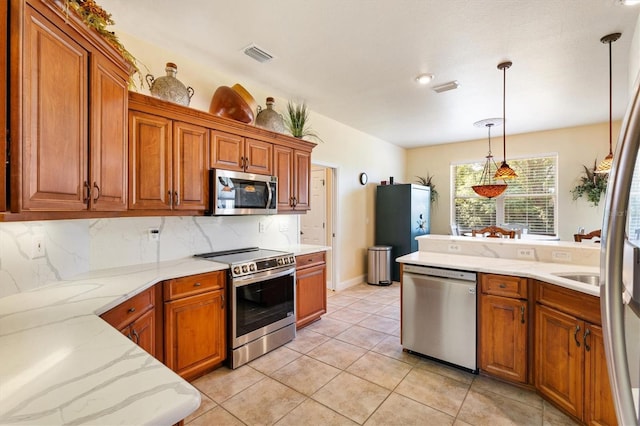 10465 SE 41st Ter, Belleview, FL 34420 - kitchen with stainless steel appliances, brown cabinetry, and hanging light fixtures