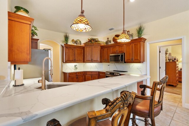 10465 SE 41st Ter, Belleview, FL 34420 - kitchen featuring appliances with stainless steel finishes, a sink, tasteful backsplash, light stone counters, and a peninsula