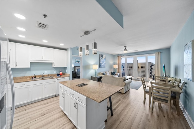 kitchen featuring a sink, white dishwasher, white cabinets, light wood-style floors, and recessed lighting