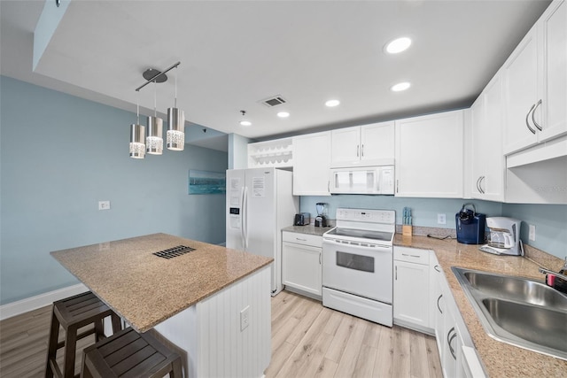 kitchen featuring white appliances, a sink, light wood-type flooring, a breakfast bar area, and recessed lighting