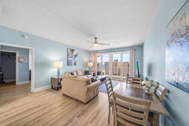 living room featuring ceiling fan, baseboards, and light wood finished floors