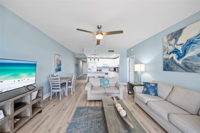 living area featuring light wood-style flooring, ceiling fan, and baseboards