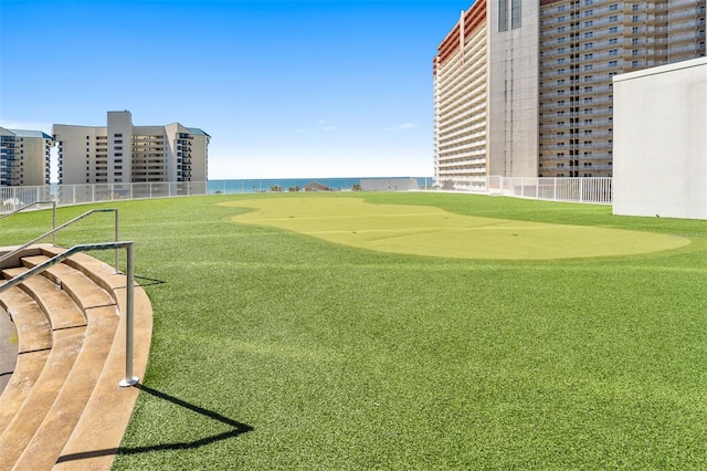 surrounding community with fence, an area to practice putting, and a water view