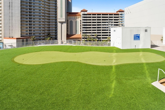 view of property's community featuring a putting green and fence