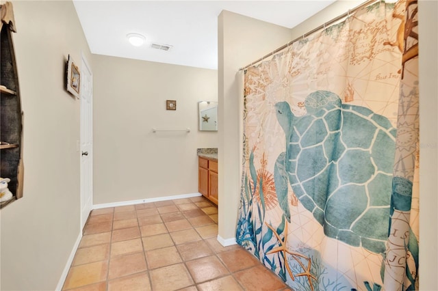 full bath featuring vanity, tile patterned flooring, and baseboards