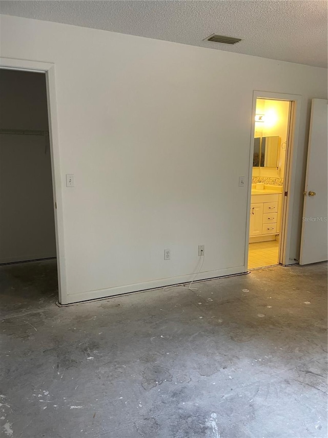 2421 Centennial Blvd, Leesburg, FL 34748 - unfurnished bedroom featuring a walk in closet, unfinished concrete floors, a textured ceiling, connected bathroom, and a closet