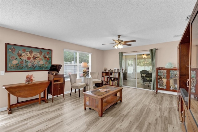 8932 SE 168th Sedgwick Pl, The Villages, FL 32162 - living room featuring light wood finished floors, a textured ceiling, plenty of natural light, and ceiling fan