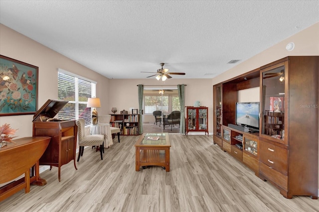 8932 SE 168th Sedgwick Pl, The Villages, FL 32162 - living area with a ceiling fan, light wood-style floors, a textured ceiling, and plenty of natural light