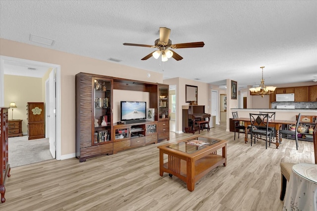 8932 SE 168th Sedgwick Pl, The Villages, FL 32162 - living room featuring light wood-style floors, a chandelier, a ceiling fan, a textured ceiling, and baseboards