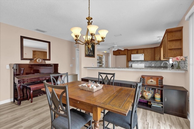 8932 SE 168th Sedgwick Pl, The Villages, FL 32162 - dining room featuring a chandelier, light wood-style floors, ceiling fan, baseboards, and a textured ceiling