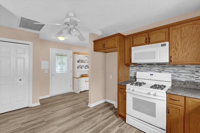 8932 SE 168th Sedgwick Pl, The Villages, FL 32162 - kitchen with white appliances, brown cabinetry, tasteful backsplash, light wood-type flooring, and a textured ceiling
