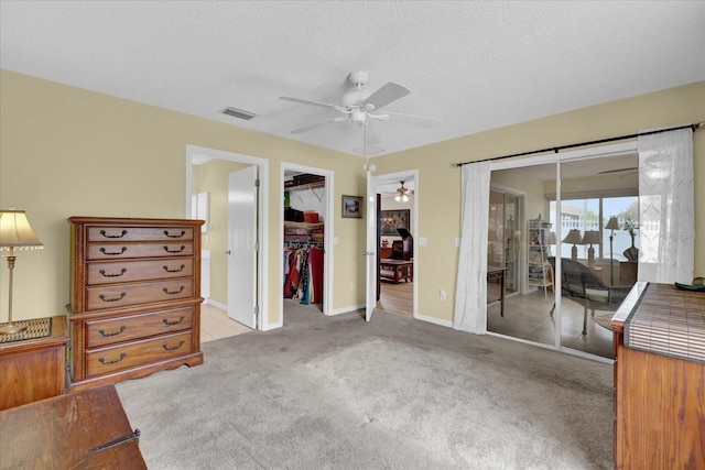 8932 SE 168th Sedgwick Pl, The Villages, FL 32162 - carpeted bedroom featuring access to exterior, a walk in closet, a closet, a textured ceiling, and a ceiling fan