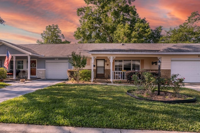 single story home featuring a garage, covered porch, concrete driveway, a front lawn, and stone siding