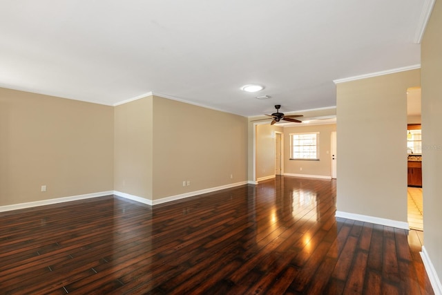 empty room featuring ceiling fan, ornamental molding, dark wood-type flooring, and baseboards