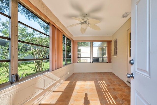 unfurnished sunroom featuring a ceiling fan and tile patterned flooring
