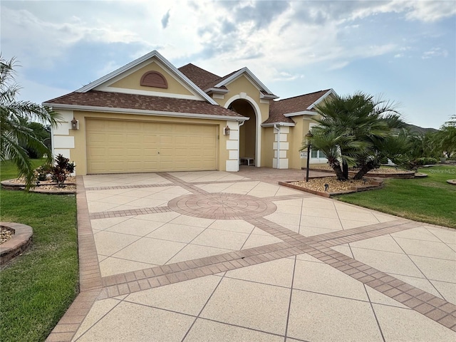 2918 Canyon Ave, The Villages, FL 32163 - mediterranean / spanish house featuring stucco siding, concrete driveway, a front yard, a garage, and roof with shingles