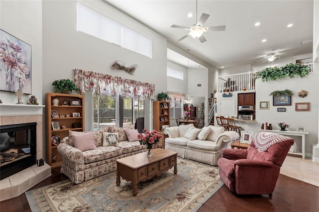living area featuring a ceiling fan, a high ceiling, recessed lighting, wood finished floors, and plenty of natural light