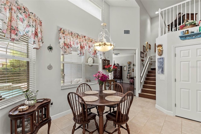 dining space featuring a high ceiling, stairs, light tile patterned flooring, baseboards, and a chandelier