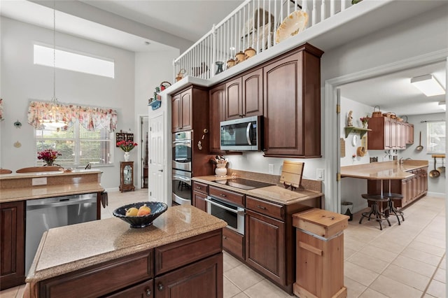 kitchen with stainless steel appliances, a high ceiling, light tile patterned flooring, decorative light fixtures, and dark brown cabinets