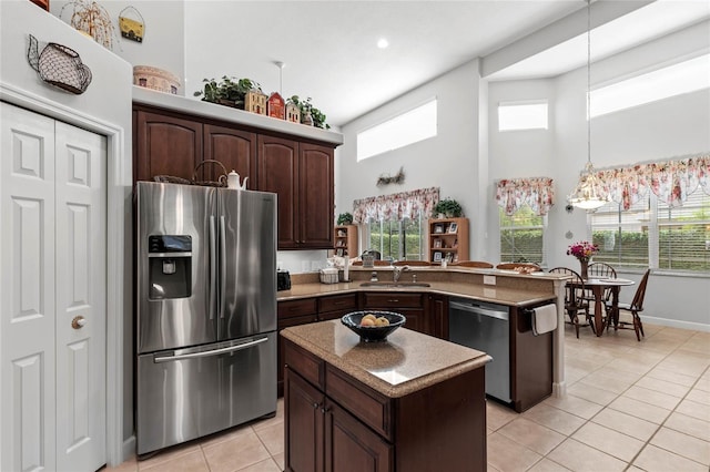 kitchen with appliances with stainless steel finishes, light tile patterned flooring, a sink, dark brown cabinets, and a high ceiling