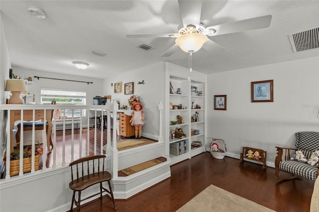 living area featuring wood finished floors, baseboards, and ceiling fan