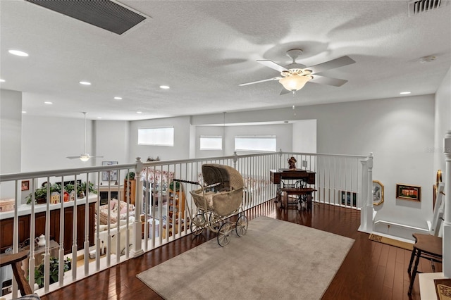 living area featuring a ceiling fan, a textured ceiling, hardwood / wood-style floors, recessed lighting, and baseboards