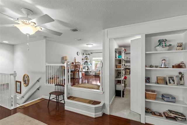 corridor featuring an upstairs landing, wood finished floors, a textured ceiling, and baseboards