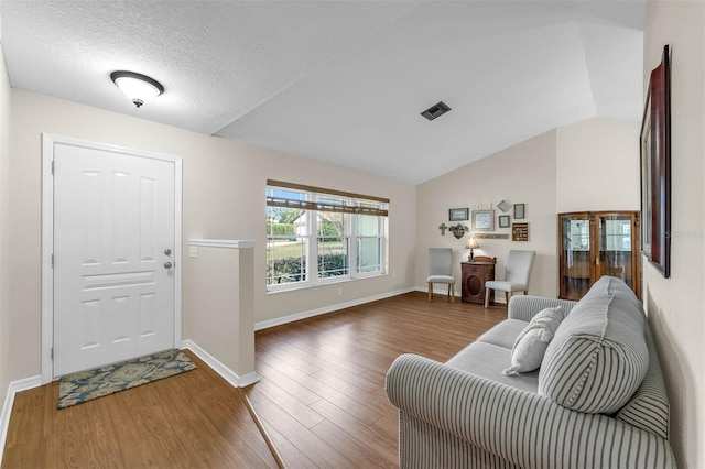foyer with wood finished floors, baseboards, and lofted ceiling
