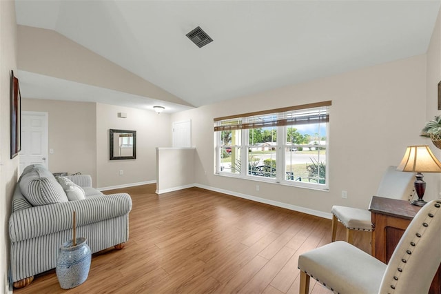 living area with vaulted ceiling, light wood-type flooring, and baseboards